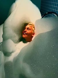 High angle view of smiling boy with eyes closed sitting in bathtub