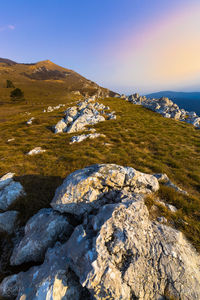 Rocks by sea against sky during sunset