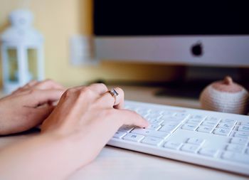 Cropped hands of woman using laptop at home