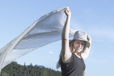 Portrait of smiling young woman against sky