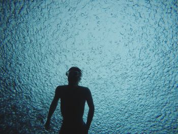 Silhouette teenage boy swimming in sea