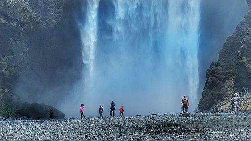 People standing against waterfall