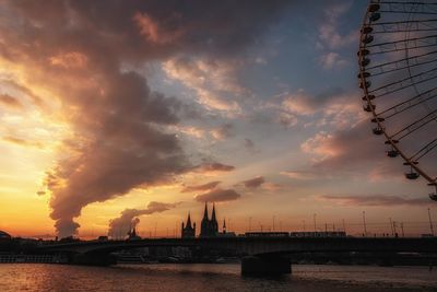 Bridge over river against cloudy sky during sunset