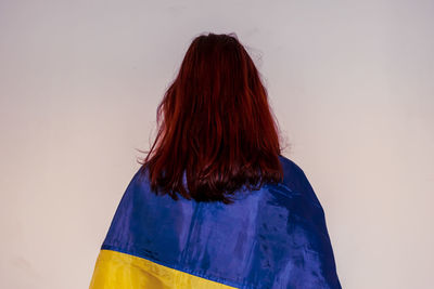 Rear view of woman standing against blue wall