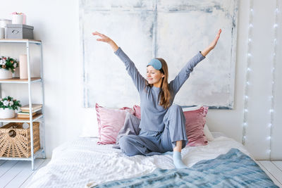Relaxed joyful caucasian young woman stretches her arms after waking up