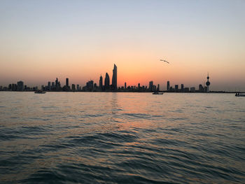 Scenic view of sea and buildings against sky during sunset