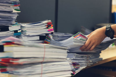 Cropped hands of businesswoman holding files on desk in office
