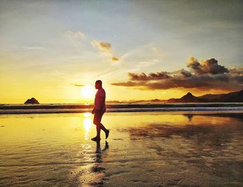 Man standing on beach against sky during sunset