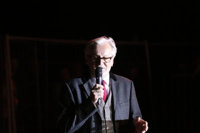 Man with arms raised standing against black background