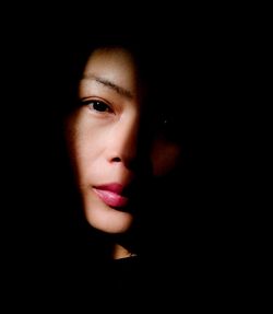 Close-up portrait of young woman against black background