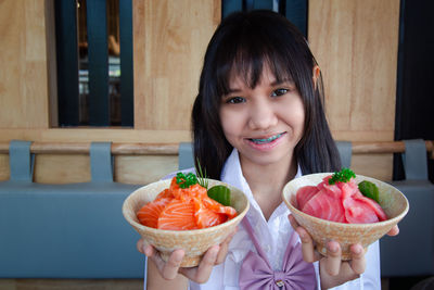Portrait of smiling woman holding strawberry outdoors