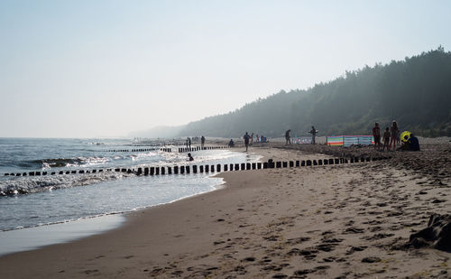 People at beach against clear sky