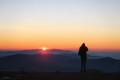 Rear view of man standing against sky during sunset