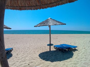 Parasols over lounge chairs on shore at beach