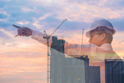 Digital composite image of architect at construction site against sky during sunset