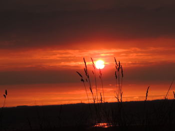 Silhouette landscape against orange sunset sky