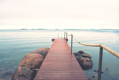 Wooden pier over sea against clear sky