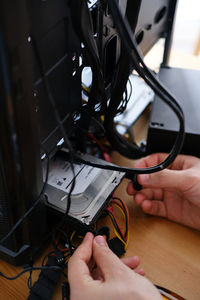 Hands of young male master install parts of pc into case.