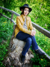 Portrait of beautiful young woman sitting against trees