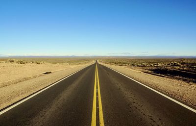 Road passing through land against clear sky