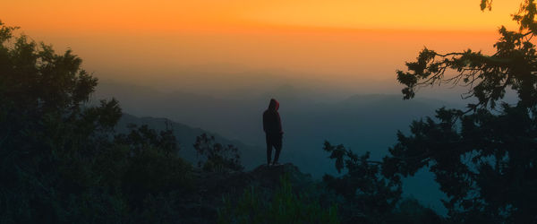 Silhouette man standing on mountain against sky during sunset