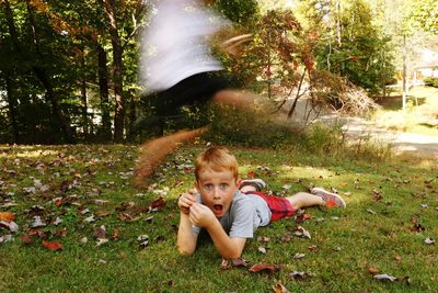 Blurred motion of friend jumping on boy lying on field