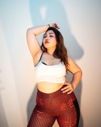 Beautiful young woman standing against wall at home