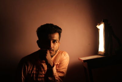 Portrait of young man looking away against wall