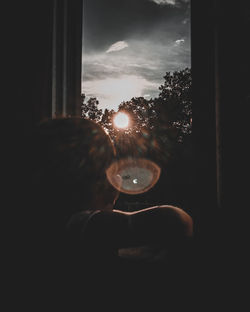 Close-up of hand holding glass window against sky during sunset