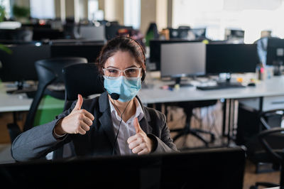 Portrait of businesswoman wearing mask gesturing at office