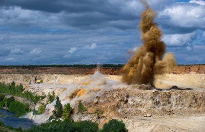 Eruption on landscape against cloudy sky