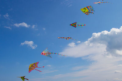 Low angle view of kites flying against sky