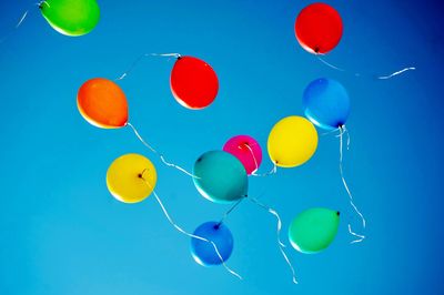 Low angle view of colorful balloons flying against clear blue sky