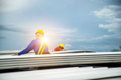 Asian construction workers are installing metal roofing sheets for industrial roof installations.