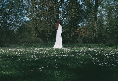 Woman standing on field against trees in forest