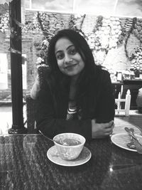 Portrait of a smiling young woman sitting on table