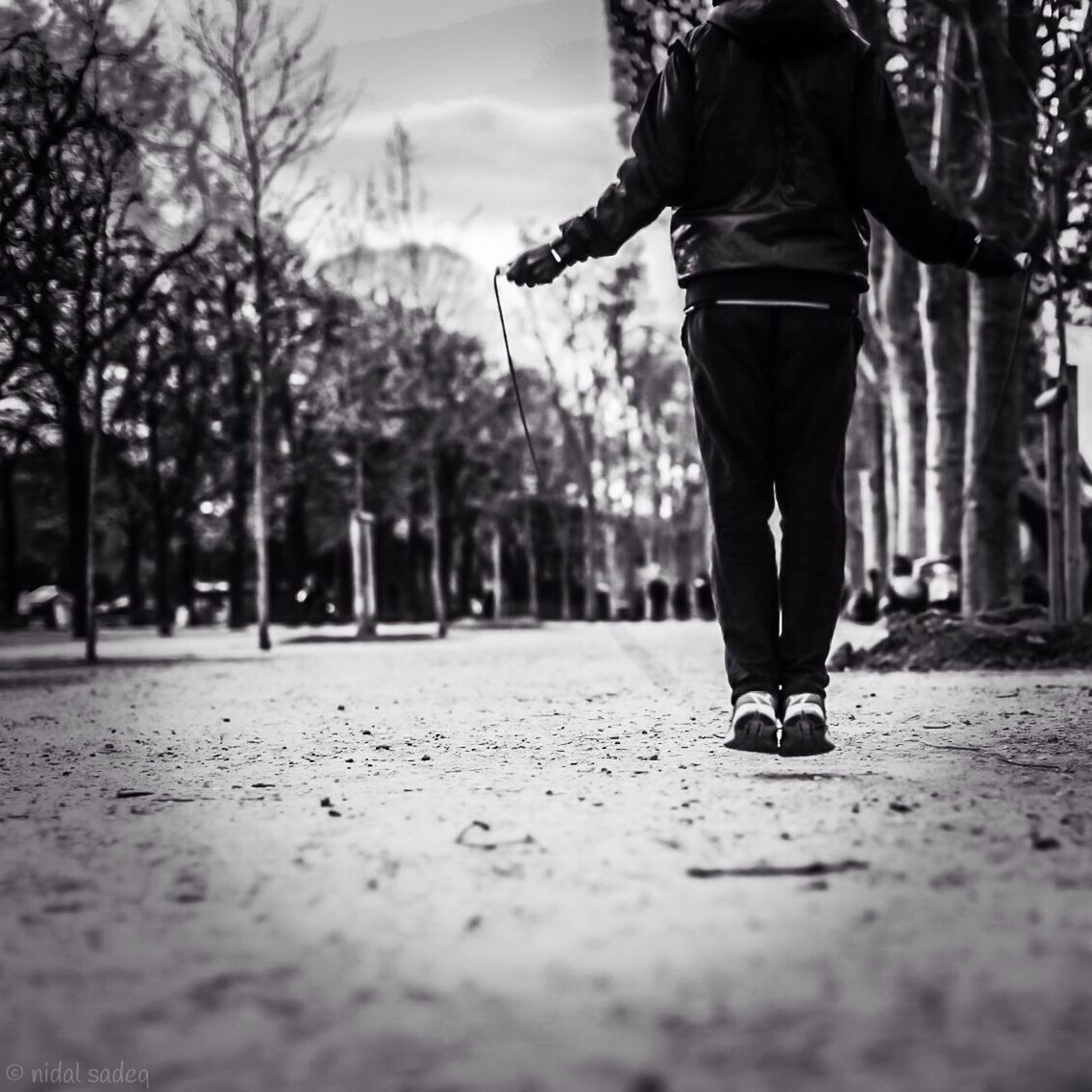 low section, tree, lifestyles, person, leisure activity, walking, men, rear view, road, full length, street, standing, casual clothing, selective focus, surface level, sky, day
