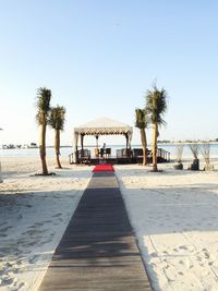 Man standing in gazebo at beach against clear sky