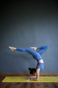 Woman with arms outstretched against blue wall