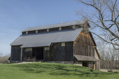 Barn on field by building against sky