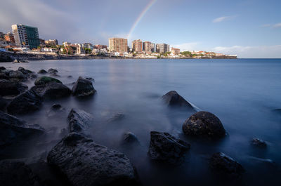 Scenic view of sea by buildings against sky
