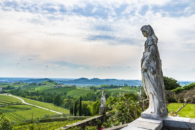 Statue amidst trees on field against sky