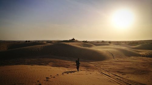Silhouette man on sand in desert against sky