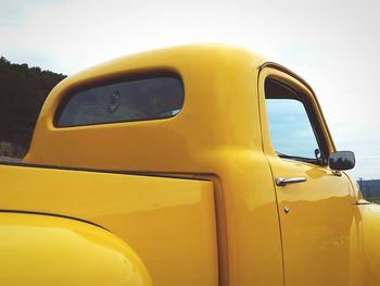 Close-up of yellow car against sky