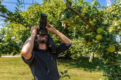 Full length of man holding apple against tree