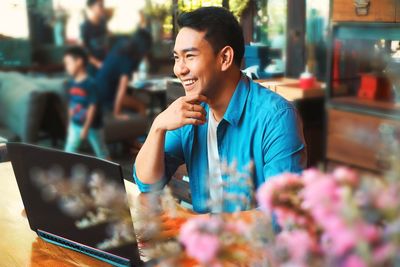 Man looking at camera while using smart phone at restaurant