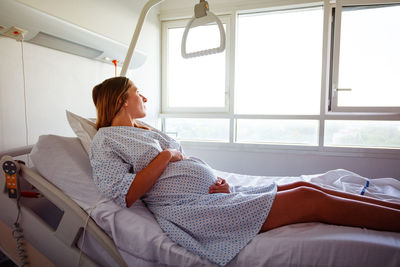 Side view of woman sleeping on bed at home