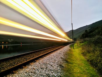 Blurred motion of train moving on railroad tracks against sky