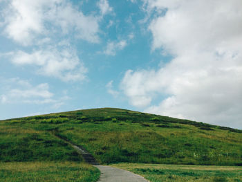 Scenic view of grassy field against cloudy sky