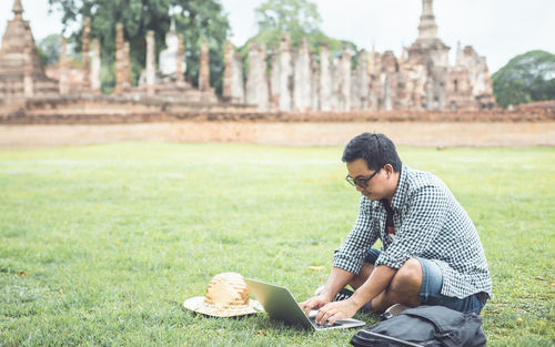 Asian tourist working and using laptop at sukhothai historical park, thailand